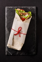 Doner kebab or shawarma sandwich on black slate background. Top view. 