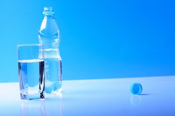 Glass and bottle wit water on blue backgrund