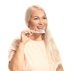 Mature woman brushing teeth on white background