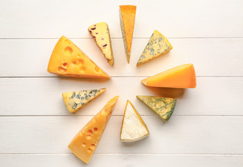 Assortment of fresh cheeses on white wooden background