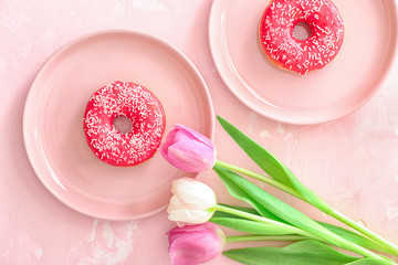 Tasty donuts and flowers on color background