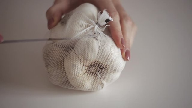 Young woman's hands peel fresh garlic head on white background