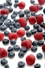 Raspberries and blueberries on white background
