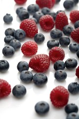Raspberries and blueberries on white background