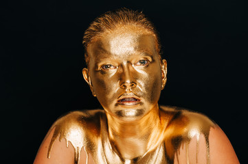 Fototapeta na wymiar Close up image of young beautiful woman covered with golden paint