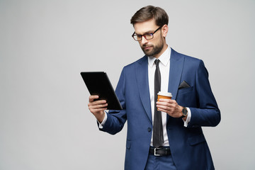 Young Businessman holding digital tablet pc pad and paper cup of coffee