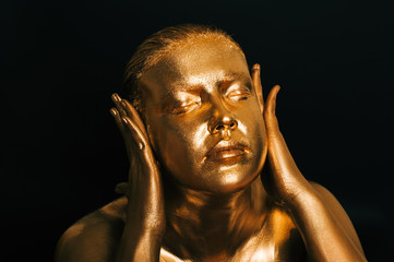 Fototapeta na wymiar Close up ortait of beautiful woman painted in gold posing as wise monkey symbol