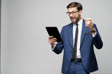 Young Businessman holding digital tablet pc pad and paper cup of coffee