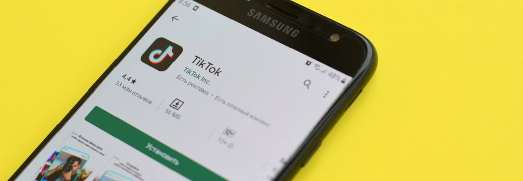 Tiktok Application In Playmarket On Samsung Smartphone Screen On Yellow Background. TikTok Is A Popular Video-sharing Social Networking Service Owned By ByteDance