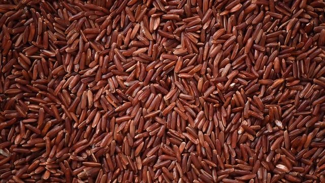 Raw dark red, balck purple rice texture on rotating background. Food ingredient background. Top view, healthy lifestyle concept.