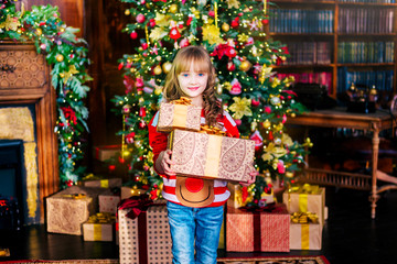 Obraz na płótnie Canvas Beautiful blonde girl stands at the Christmas tree with gifts. Holidays, sale concept.