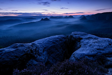 Kleiner Winterberg, morning view over sandstone cliff into deep misty valley in Saxony Switzerland,...