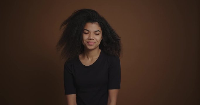 Portait of african american girl looking coquettishly at camera brown background