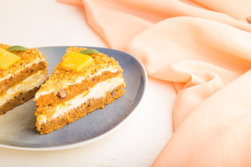 Homemade cake with persimmon and pumpkin on a white wooden background with orange textile. side view, selective focus.