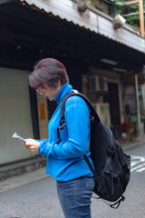 Solo traveller vacations in Asia. Woman tourist using map for searching direction, exploring locations in streets of city while enjoying solo trip in Taipei Taiwan. copy space.