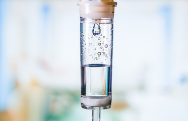 Dripping medical perfusion close up equipment in clinic background. Saline Solution IV Drip Fluid for Infusion in Hospital. Intravenous infusion tube equipment in hospital. Health patient concept.