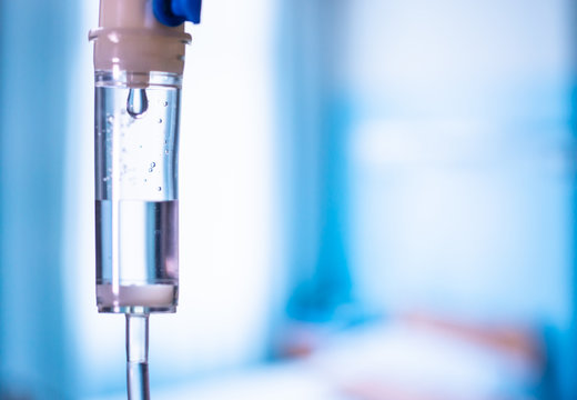 Dripping medical perfusion close up equipment in clinic background. Saline Solution IV Drip Fluid for Infusion in Hospital. Intravenous infusion tube equipment in hospital. Health patient concept.