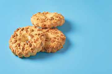 Heap of three fresh circle oat cookies with hole and peanuts lies on blue desk on kitchen. Space for text