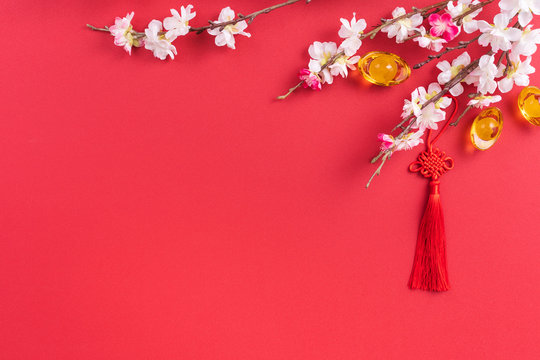 Design concept of Chinese lunar new year - Beautiful Chinese knot with plum blossom isolated on red background, flat lay, top view, overhead layout.