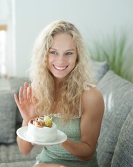 Happy woman gesturing while holding cake in house