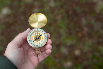 A person lost in nature tries to orient himself with a compass in a forest with fog