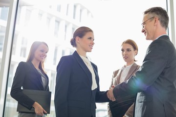 Confident business people shaking hands in office