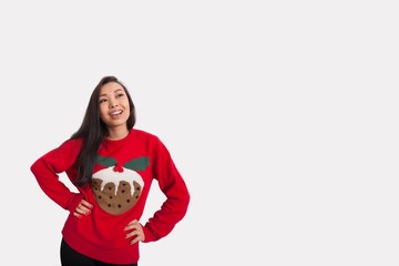 Young woman in Christmas sweater standing with hands on hips over gray background