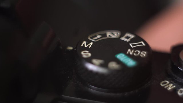 Professional photographer set mode wheel to manual mode on photo or video camera. Extreme close up