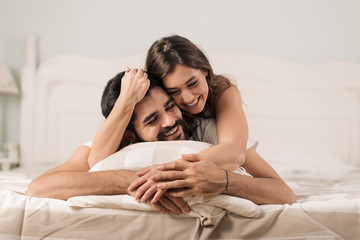 Young happy couple having fun while laughing in the bed