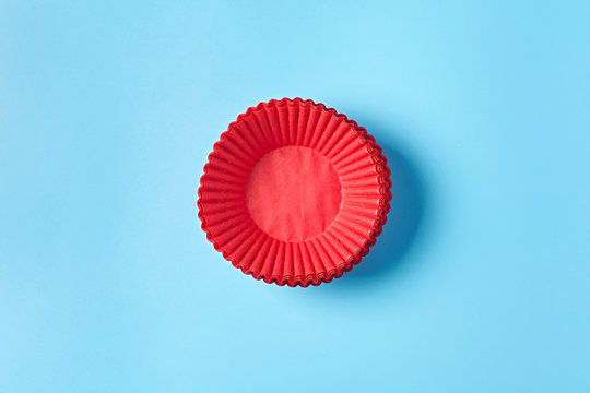 Heap Of New Red Paper Molds For Baking Muffins Lies On Blue Desk On Kitchen. Close-up. Top View