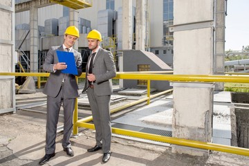 Full length of young male architects looking at clipboard on construction site