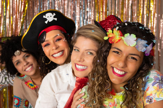 Carnival in Brazil. Group portrait of friends dressed in Hawaiian, Pirate and Hippie costumes. Cheerful friends in costume enjoying Carnival in Brazil and looking at camera