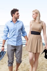 Romantic young couple holding hands and walking on beach