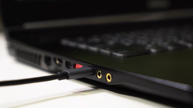 Close up male hand connect gray and black type-c cable to laptop with glowing red usb port.