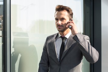 Young businessman using cell phone outside office building