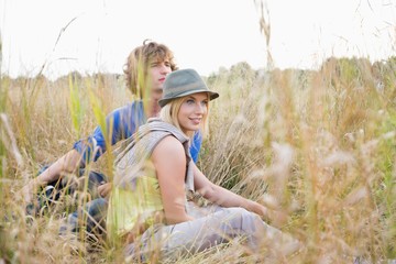 Young couple looking away while relaxing in field