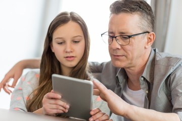 Father and daughter using digital tablet at home