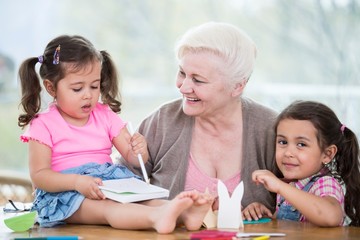 Happy senior woman with granddaughters making handicraft at home