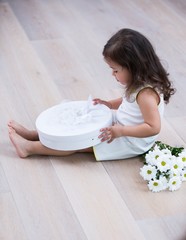 Full length side of little girl opening gift box on floor at home