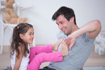 Father tickling daughter's foot at home