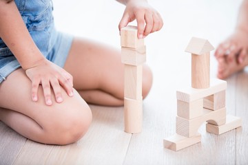 Midsection of girl playing with building blocks on hardwood floor