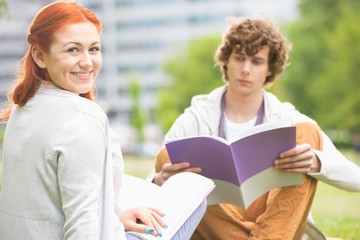 Portrait of happy young woman with male friend studying at college campus