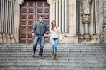 Full length of young couple moving down steps against building