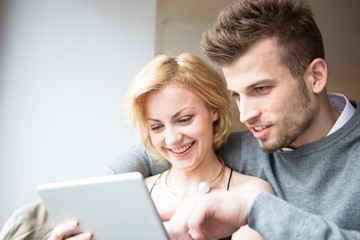 Happy young couple using digital tablet in cafe