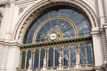Fototapeta na wymiar Old city railway station exterior detail. Glass detail on facade with clock