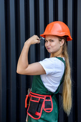 Beautiful woman in helmet and coverall holding fixing key over eye