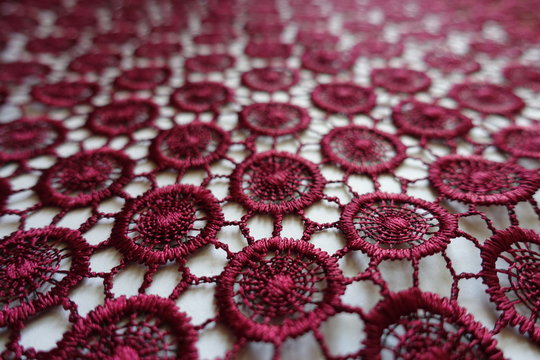 Macro of dark red lacy fabric with circular pattern