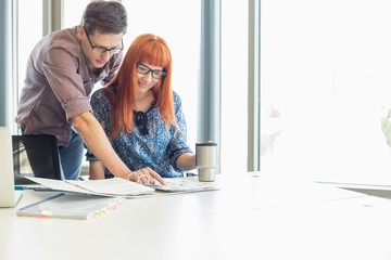 Businesspeople analyzing file together at desk in creative office