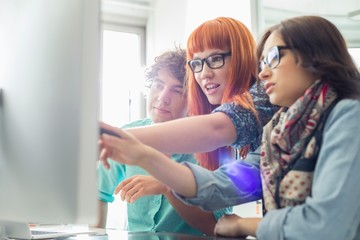 Business colleagues discussing over computer in creative office