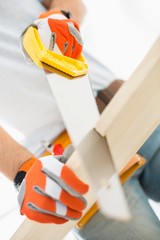 Midsection of man sawing plank